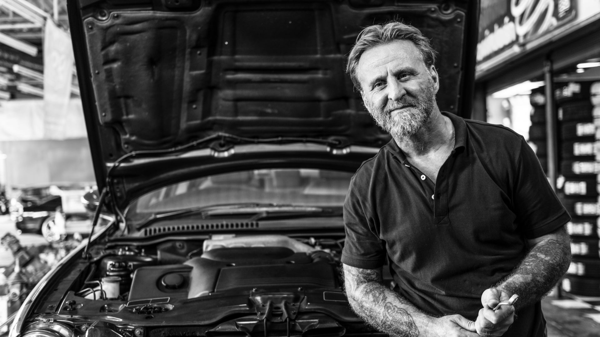 a mechanic smiling in front of his car